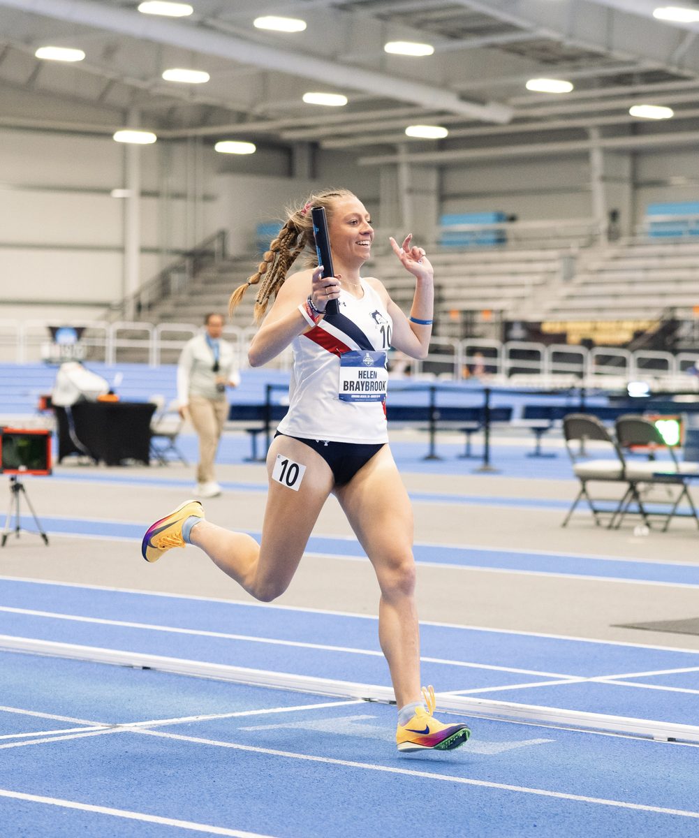 Helen Braybrook running a relay leg on an indoor track